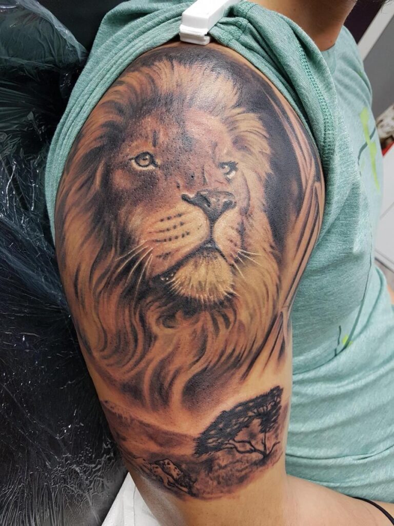 Detailreiches Löwentattoo auf dem Oberarm eines Mannes . Tattoo in Hamburg von Ozzy gestochen