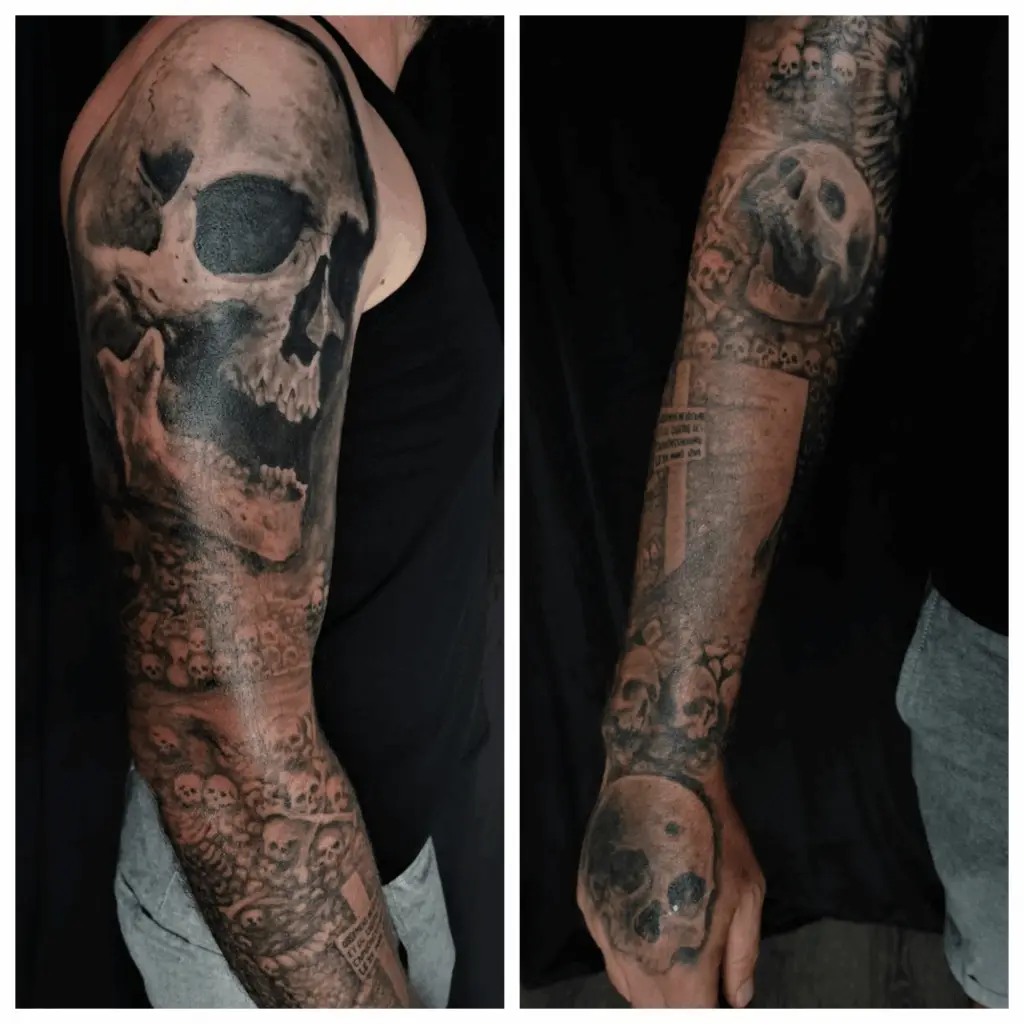 Detailreiche Tattoos eines großen Schädels und vielen kleinen als Teil der Pariser Katakomben als Sleeve auf dem Arm. Tattoo in Hamburg von Ozzy gestochen