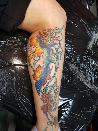 Ein großer, farbenprächtiger Vogel, der Phönix und Pfau vereint, als Tattoo auf der Wade. Bunter-Vogel-Tattoo von Ozzy in Hamburg gestochen.Tattoo von Ozzy in Hamburg gestochen.
