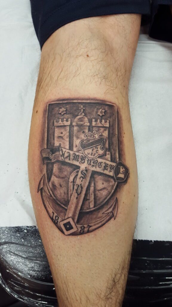 Hamburg-Tattoo mit dem Hamburger Wappen und einem Anker mit dem alten HSV-Logo. HSV-Hamburg-Wappen-Tattoo von Ozzy in Hamburg gestochen.