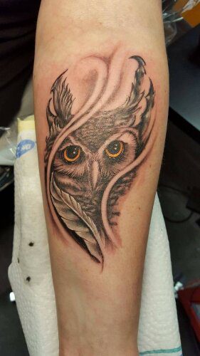 Detailliertes Tattoo eines Eulengesichtes mit sanften Federn im Hintergrund . Tattoo in Hamburg von Ozzy gestochen