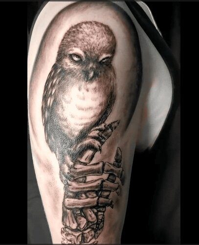 Realistisches Tattoo eines Eulen-Tattoos mit einer Skeletthand auf dem Oberarm. Tattoo in Hamburg von Ozzy gestochen