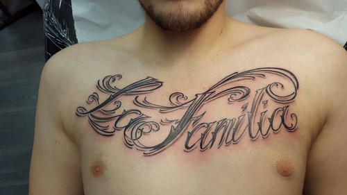 Ein großer "La Familia" Schriftzug als Black and Grey Tattoo auf der Brust. Tattoo von Ozzy in Hamburg gestochen